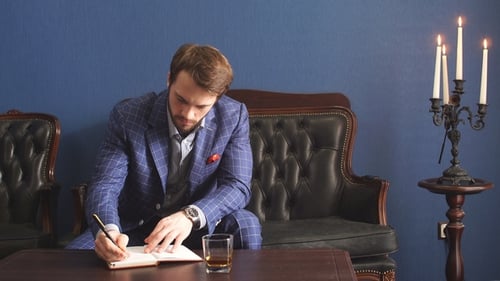 Handsome Young Writer in a Classy Suit Having an Inspiration Mood Making Some Notes , While Sitting