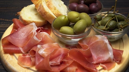 Tranches de prosciutto sur une planche de bois et du pain