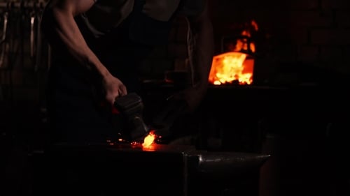 Blacksmith Forging Hot Metal in Dark Workshop