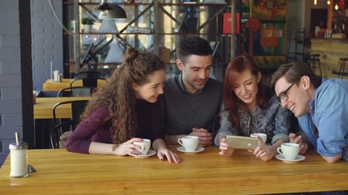 Friends Looking at Smartphone in Coffee Shop