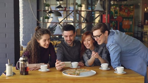 Friends Video Calling on a Smartphone in Cafe