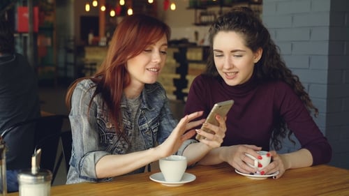Two Women Enjoying Phone and Coffee at Cafe
