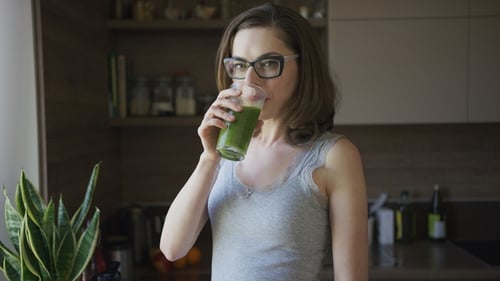 Woman Enjoying Green Smoothie in Sunny Kitchen