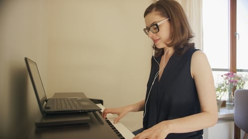 Woman Plays Electric Piano at Home with Laptop