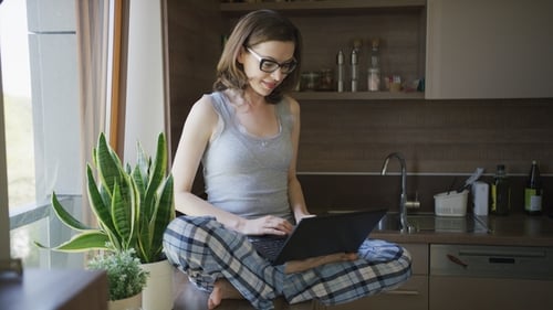 Woman Using Laptop in Kitchen at Home