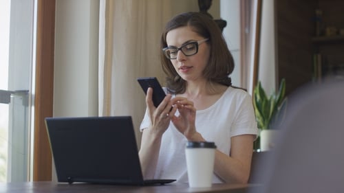 Woman Typing on Laptop and Talking on Phone