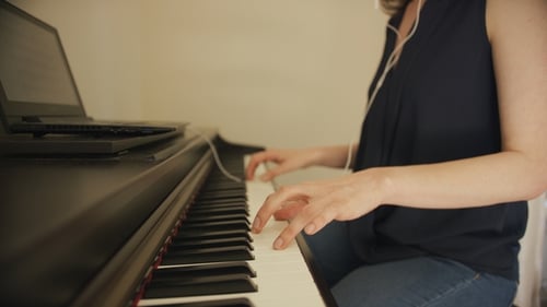 Woman Playing Piano with Headphones Indoors