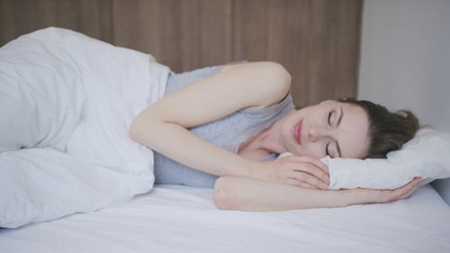 Woman Sleeping Peacefully in Bright Bedroom