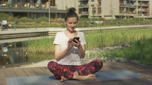 Woman Using Phone, Meditating Outdoors in Urban Park