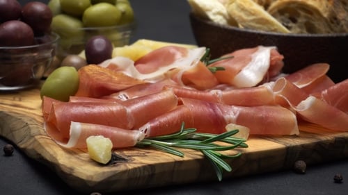 Tranches de prosciutto sur une planche de bois et du pain