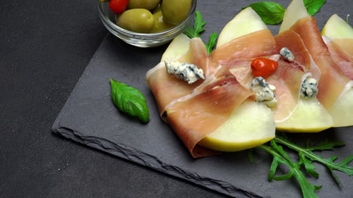 Tranches de prosciutto et de melon sur une planche en pierre