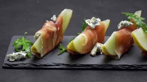 Tranches de prosciutto et de melon sur une planche en pierre