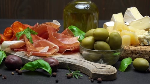 Sliced Prosciutto or Jamon Meat and Cheese on Concrete Background