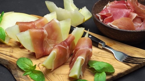 Tranches de prosciutto et de melon sur une planche de bois