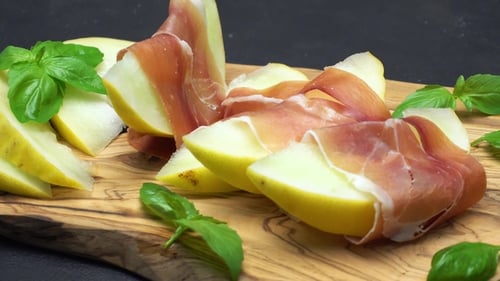 Tranches de prosciutto et de melon sur une planche de bois