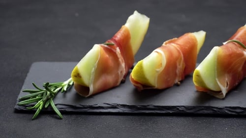 Tranches de prosciutto et de melon sur une planche en pierre
