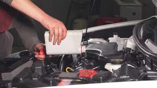 Mechanic Adding Oil to Car Engine in Garage