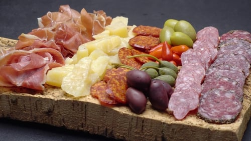 Tranches de saucisse au prosciutto, au fromage et au salami sur une planche à découper en liège
