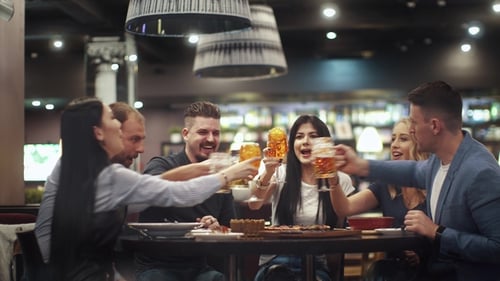 Friends Toasting Drinks at Restaurant Table at Night