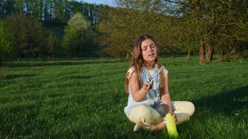 Girl Blowing Soap Bubbles in Spring Park.