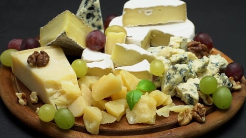 Assorted Cheeses and Grapes on a Wooden Board