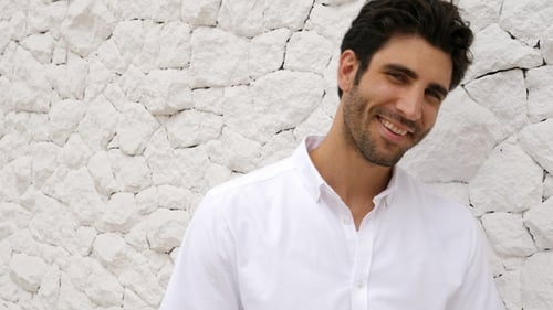 Attractive Man Smiling Leaning Against White Stone Wall
