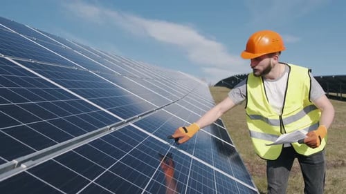 Männlicher Ingenieur in Uniform überprüft draußen die Solarbatterie