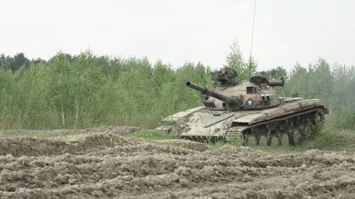 Military Tank Traversing Rural, Muddy Landscape