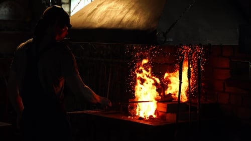 Blacksmith Fanning the Flames of the Furnace Using the Tools Prevents Embers