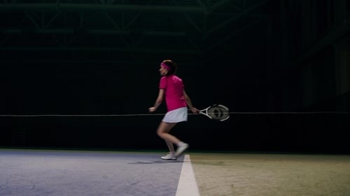 Female Tennis Player Hitting Ball on Indoor Court