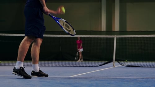 Man Hitting Tennis Ball on Indoor Court