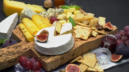 Gourmet Cheeses with Grapes and Figs on Rustic Board