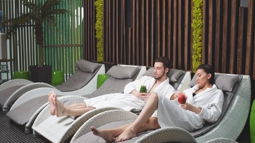 Pensive Couple in the White Bathrobes Sitting in the Loungers in Spa Center