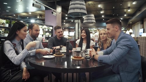 Large Group of Friends Talking and Having Fun Together Sitting at a Table in a Cafe or Restaurant