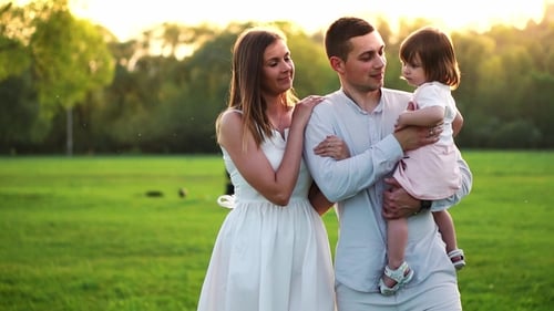 Happy Young Family with Child Walking on Summer Field