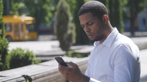 African American Man Sms Texting Using App on Smart Phone in City