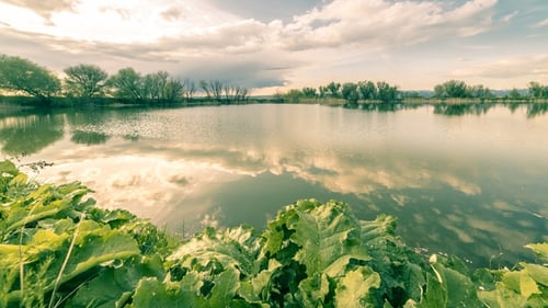 Schöne Wolken am blauen Himmel mit Spiegelung im ruhigen Wasser im Morgensee. Natur-Tapete.