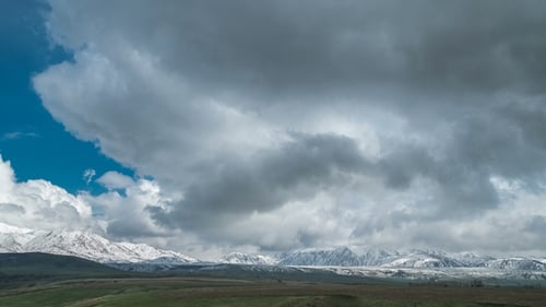 Blue Sky with Clouds Over the Snow-capped Mountain Peaks in Kazakhstan.