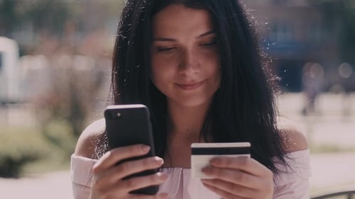 Woman using phone with credit card for online shopping