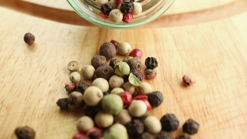 Mixed Peppercorns Pouring onto Wooden Board