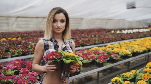 Young Woman Holding Flowers in a Greenhouse