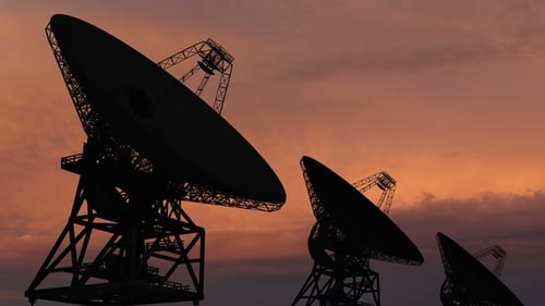 Satellite Dishes Moving in Against a Sunset Sky