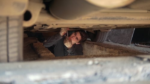 Auto Mechanic Repairing Car in Service Pit