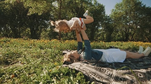 Mother and Daughter Lying on Lawn. Family Having Fun in City Park Outdoors