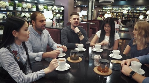 Large Group of Friends Talking and Having Fun Together Sitting at a Table in a Cafe or Restaurant