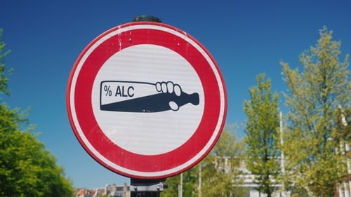 A Traffic Sign Prohibiting Alcohol Consumption in a Public Place. A Bottle of Alcohol on a White