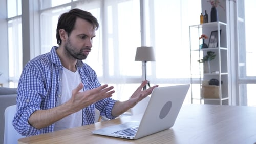 Hombre molesto enojado con barba casual trabajando en la computadora portátil en la oficina