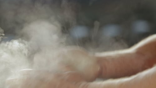 Un athlète fort se frotte les mains avec du magnésium. La poussière est