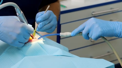 Dentist Working on Patient's Teeth with Assistant