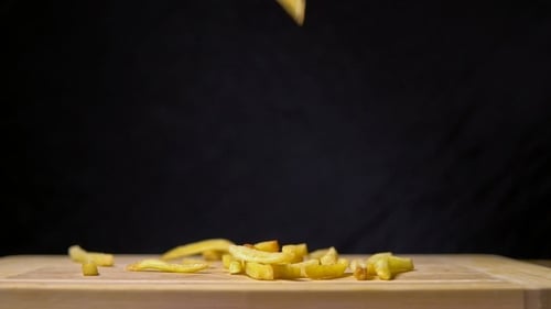 Golden French Fries Falling on Cutting Board